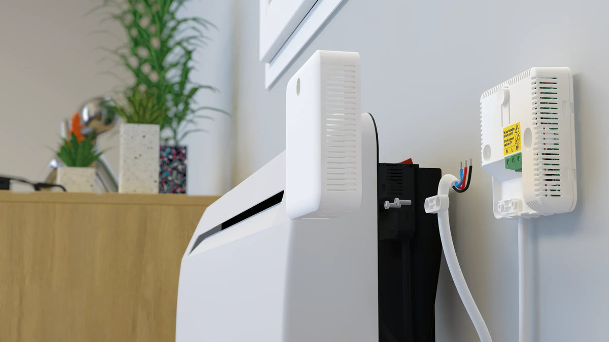 Actionneur Chauffage Électrique Zigbee NodOn fixé au mur au niveau de la sortie de câble du radiateur
